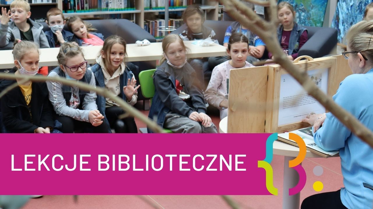 Grupa dzieci słucha przemowy kobiety w bibliotece, w tle widać regały z książkami i obrazy. Na obrazku widenieje napisa "LEKCJE BIBLIOTECZNE"
