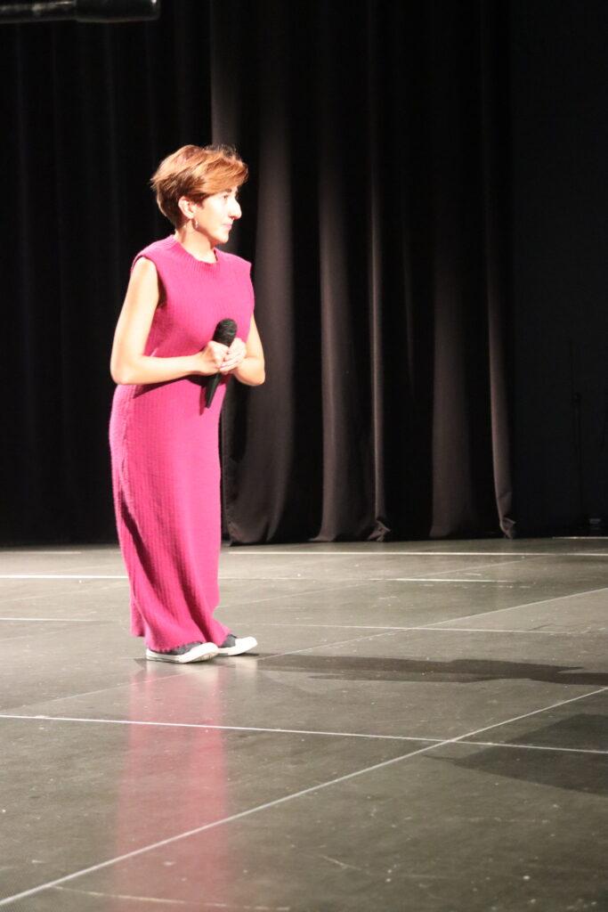 Kobieta stoi na scenie z mikrofonem w dłoniach