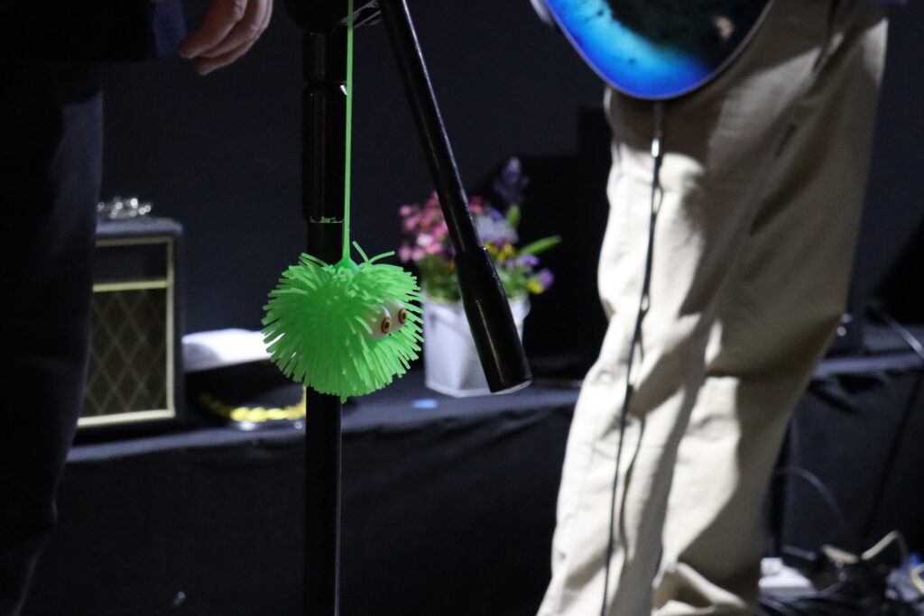 Gumowa, zielona, okrągła zabawka wisząca na stojaku do mikrofonu.