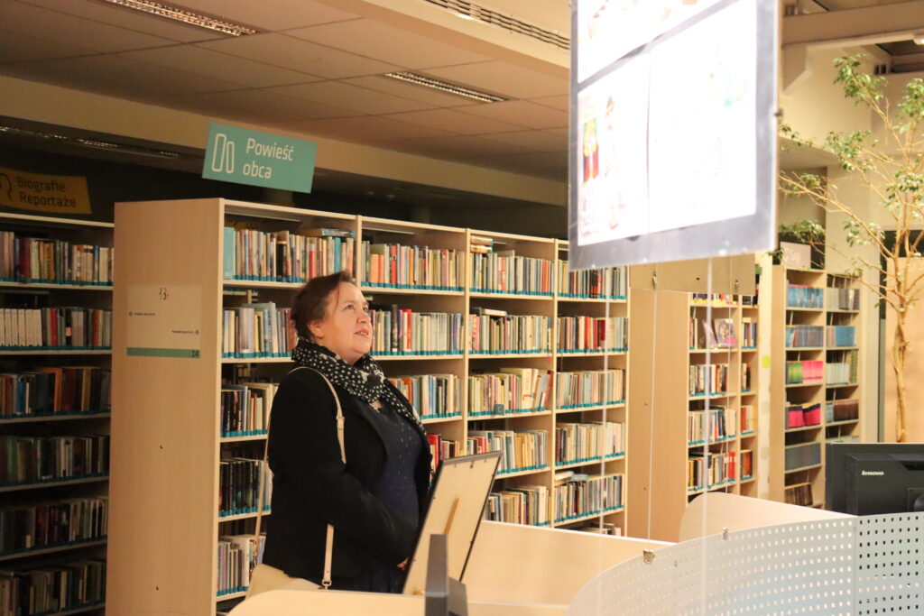 Kobieta w ciemnym ubraniu ogląda wystawę.