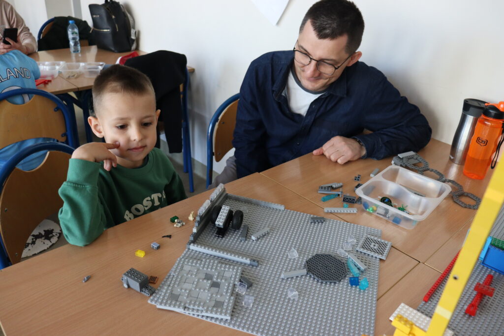 Chłopiec z tatą budują z klocków.