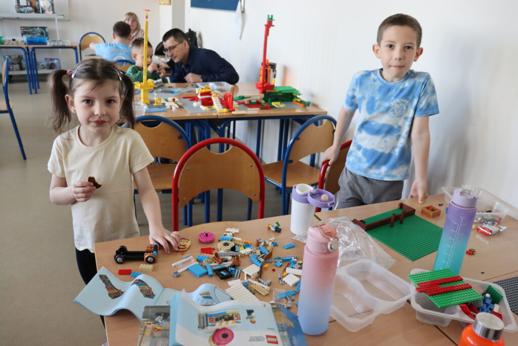 Chłopiec i dziewczynka stoją przy stole z klockami.