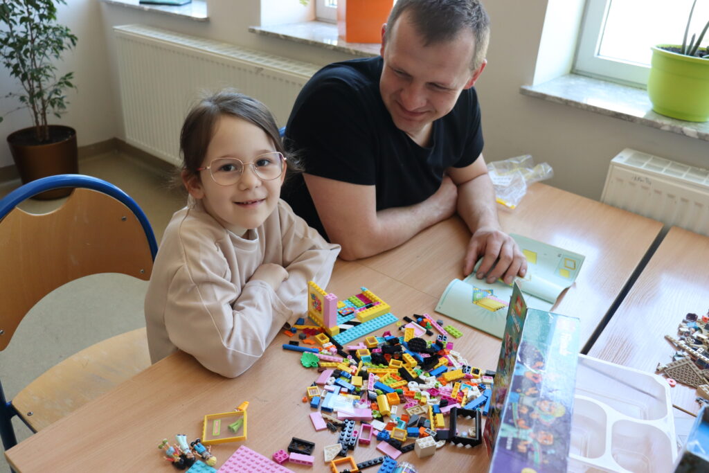 Dziewczynka i tata budują z klocków.