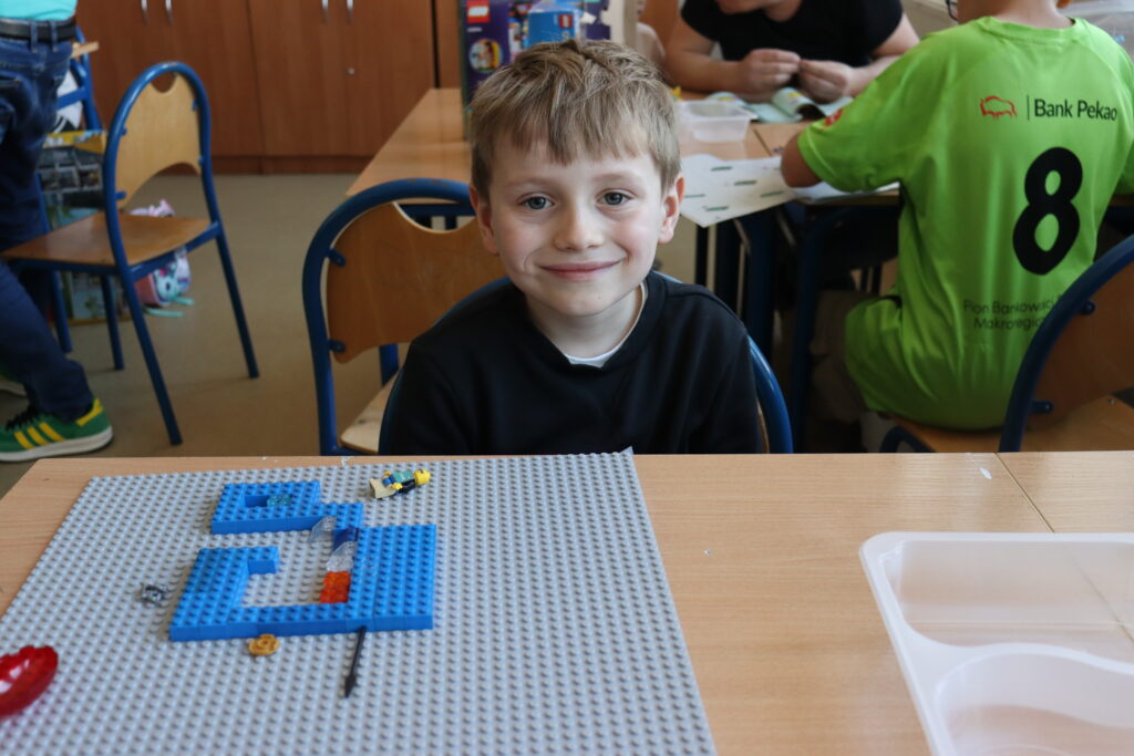Uśmiechnięty chłopiec siedzi przy stole z klockami.