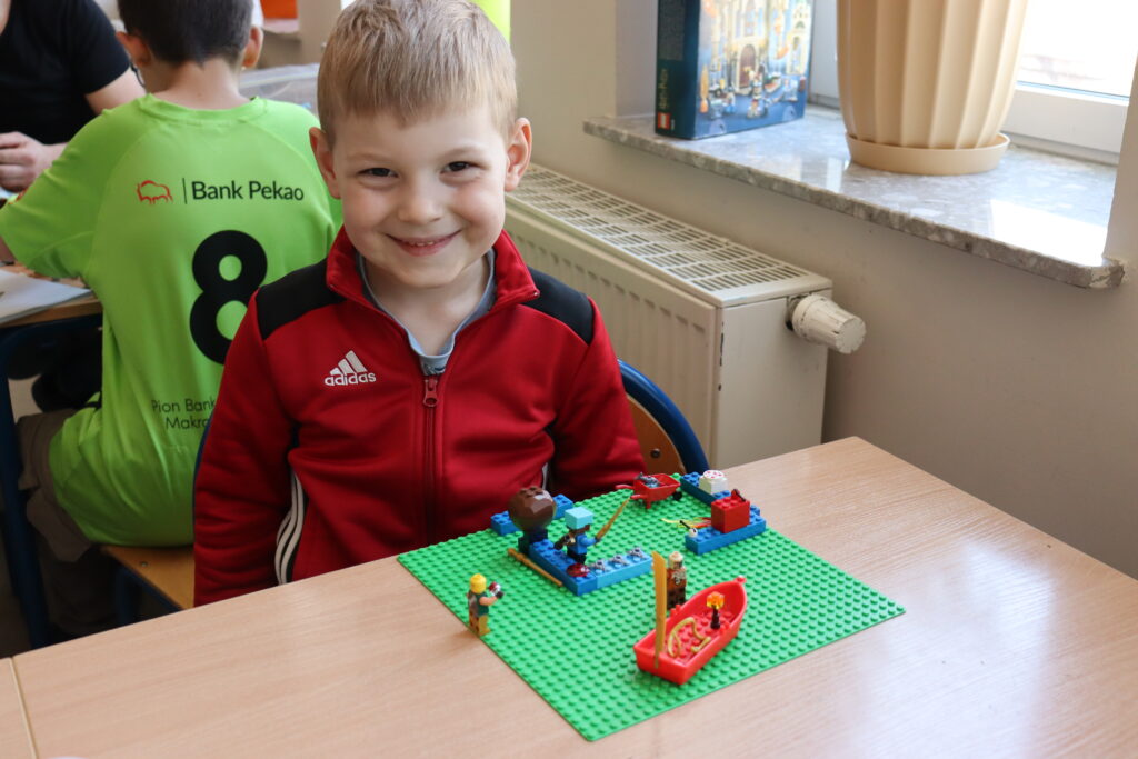 Uśmiechnięty chłopiec siedzi przy stole z klockami.