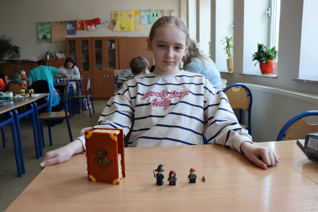 Dziewczynka i zbudowany zestaw lego Harry Potter.