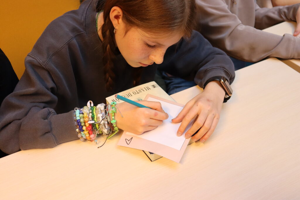 Dziewczynka z warkoczami rysuje na kartce.