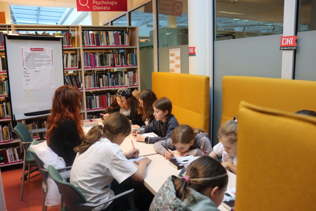 Klubowicze siedzą przy stole.