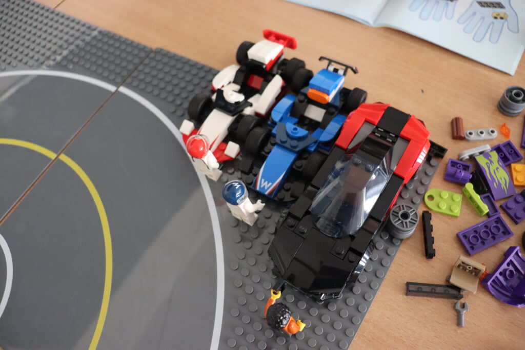 Trzy autka zbudowane z klocków LEGO.