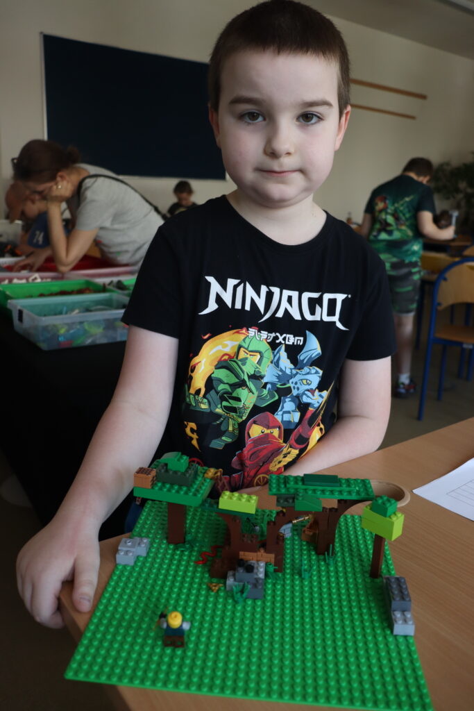 Chłopiec w koszulce z LEGO Ninjago pokazuje zbudowaną dżunglę.