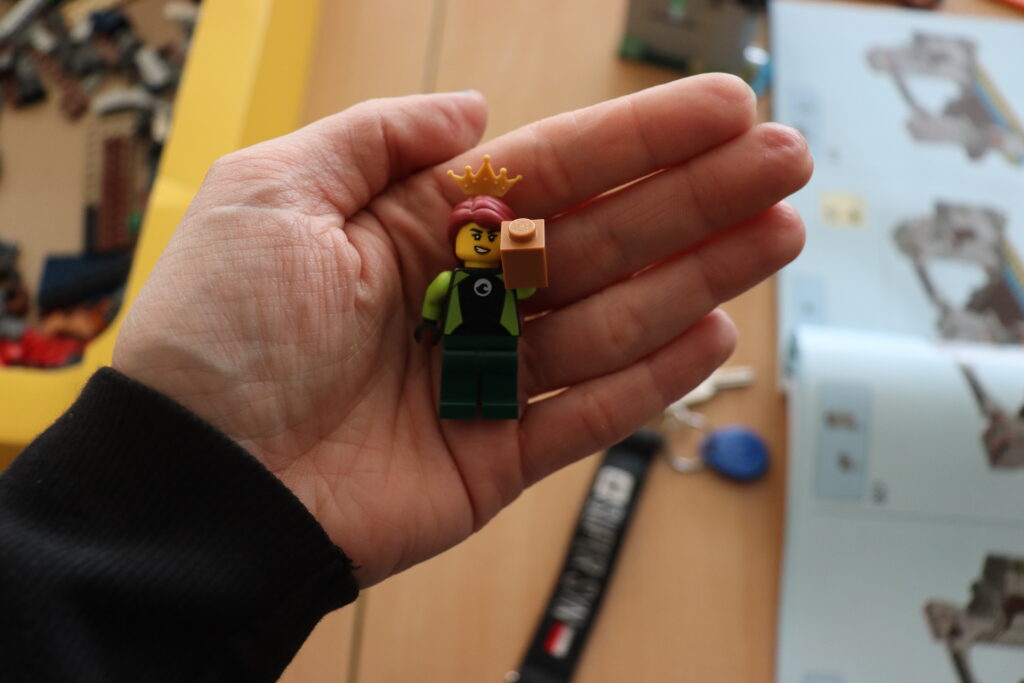 Ludzik LEGO w koronie i z klockiem w ręce.
