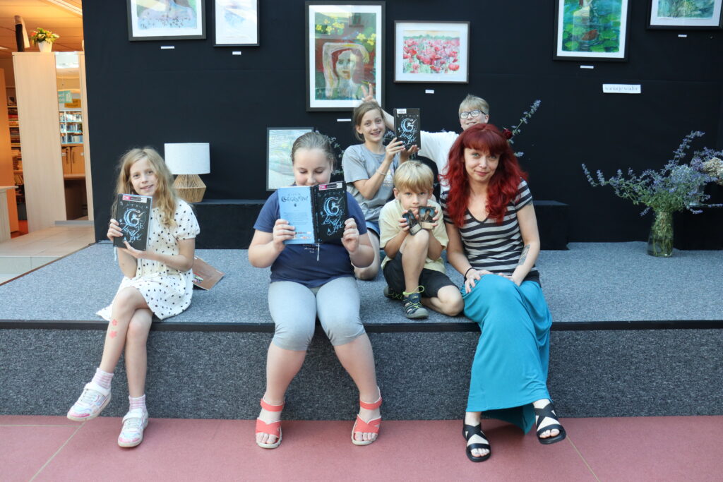 Członkowie klubu i bibliotekarka pozują na scenie z książkami "Gwiezdny pył".